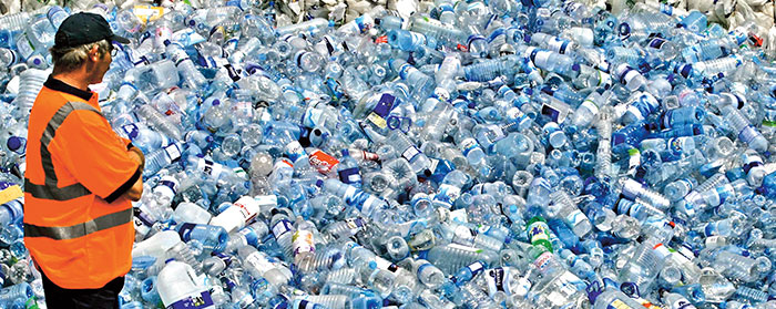 a man looking at a large pile of empty plastic bottles