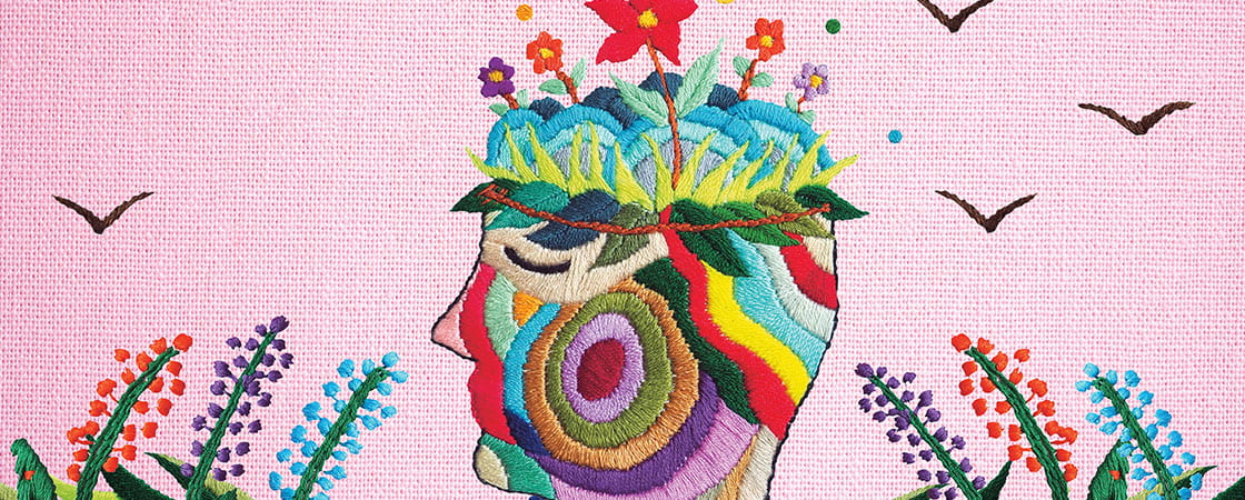 A colorful illustration of a face with flowers growing out of it and beautiful threads as skin