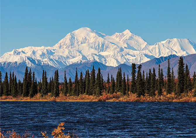 Enlargeable photo of snow capped mountains overlooking a forest and river