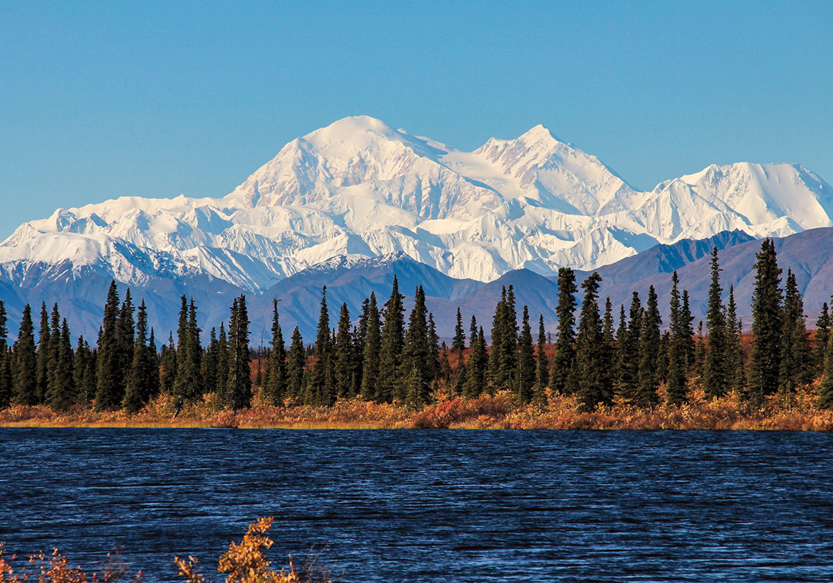 Snow capped mountains overlooking a forest and river