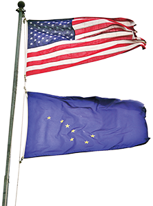 A flag pole with the American flag and the Alaskan state flag under it