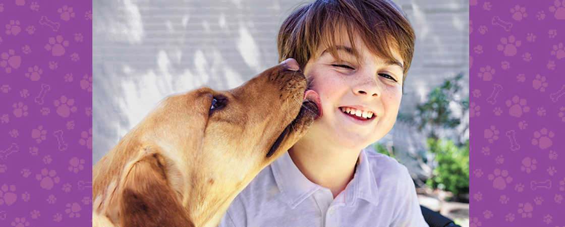 Photo of a dog licking a child&apos;s cheek